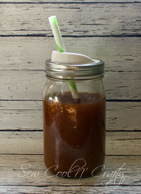 a mason jar filled with brown liquid and a green straw sticking out of the top