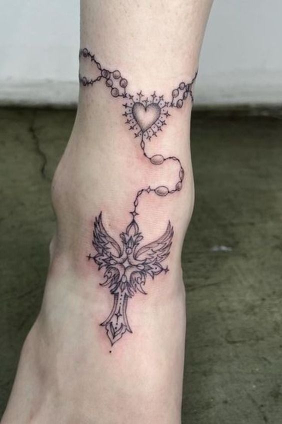 a woman's foot with a cross and heart tattoo on the top of it