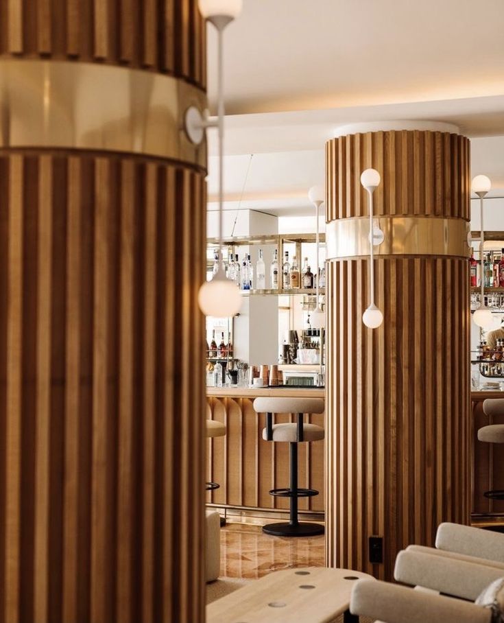 the interior of a modern bar with wooden columns and stools, along with bars