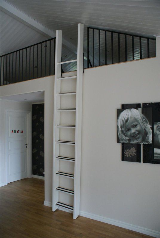 there is a white ladder in the room with pictures on the wall next to it