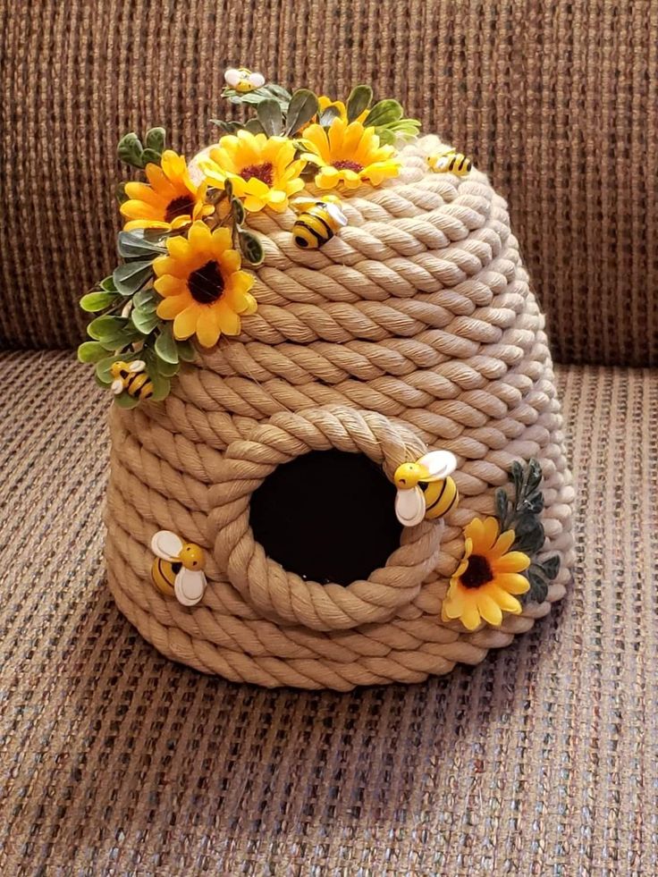 a birdhouse made out of rope with sunflowers and leaves on the top