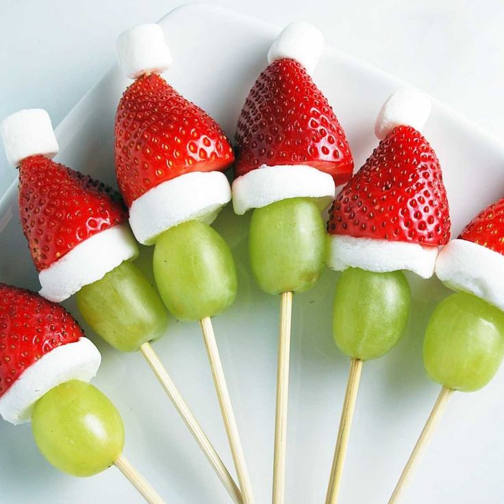 strawberries and grapes are arranged on skewers with santa's hat hats