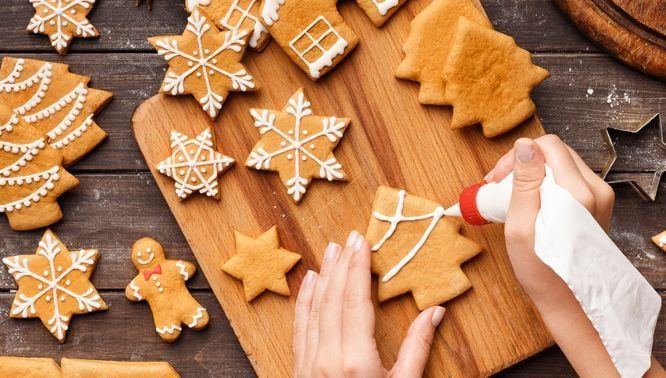 someone decorating christmas cookies on a cutting board