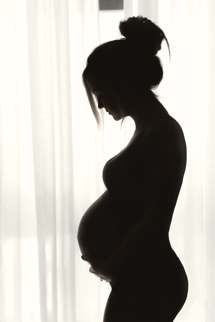 a pregnant woman standing in front of a window