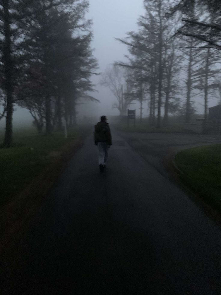 a person riding a skateboard down a road in the fog