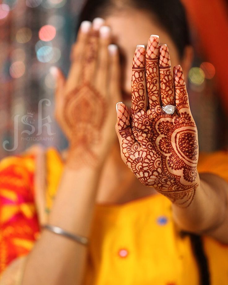 a woman holding her hands up with henna on