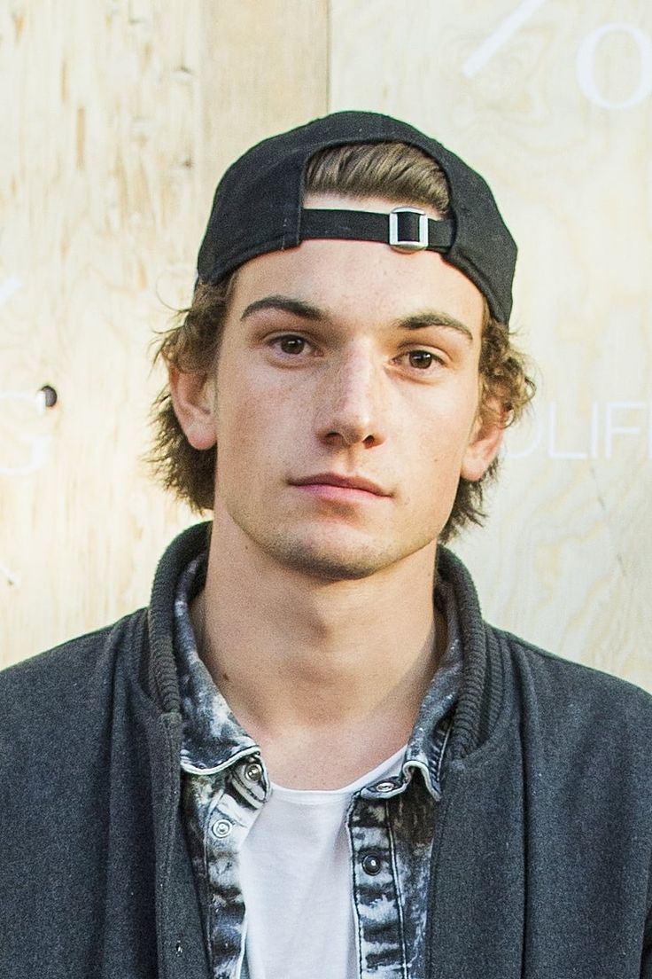 a young man wearing a baseball cap and looking at the camera with a serious look on his face