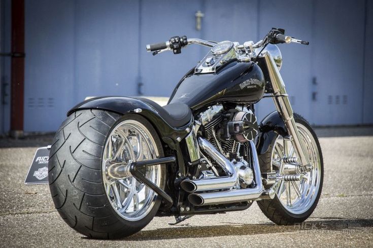 a black motorcycle parked on top of a parking lot next to a blue garage door