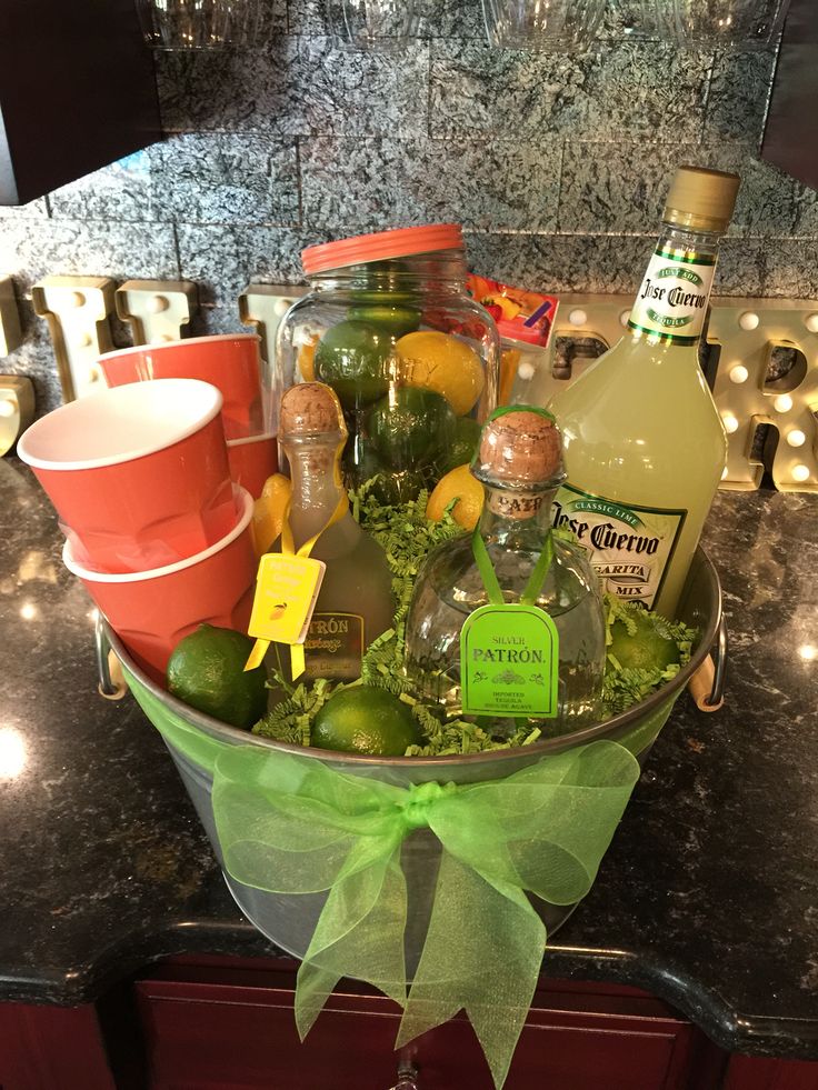 a bucket filled with liquor bottles and limes on top of a counter next to cups