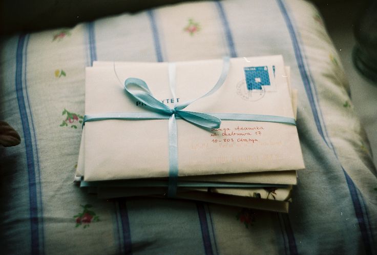 three envelopes wrapped in blue ribbon on a bed