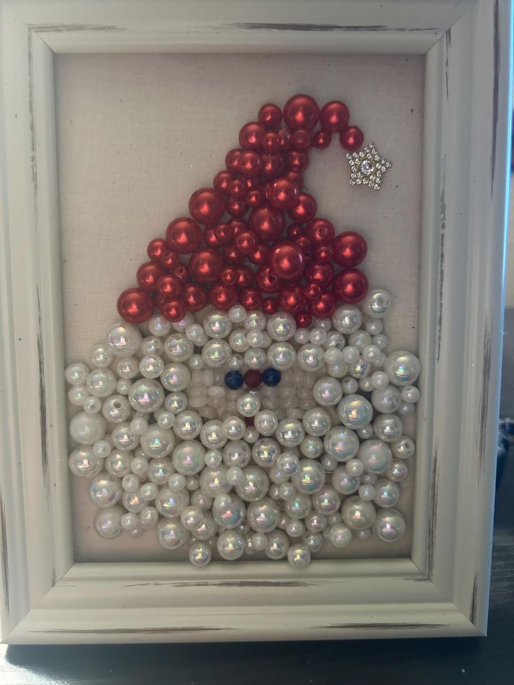 a white frame with red and white beads in the shape of a santa clause hat