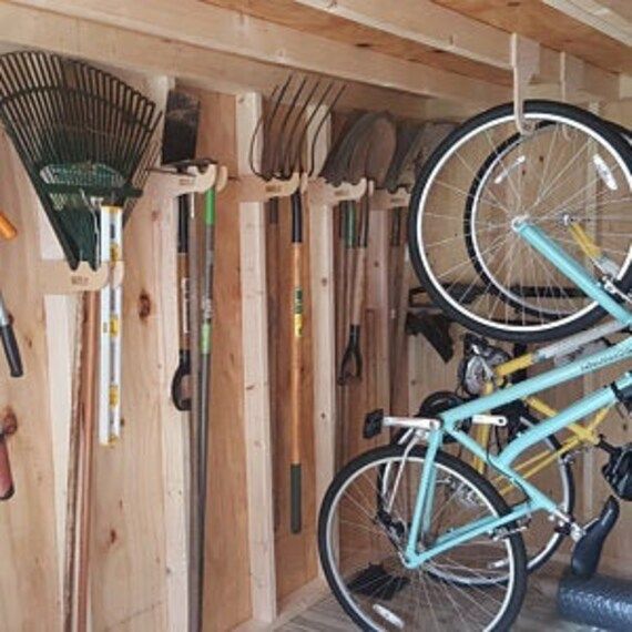 there is a bike hanging on the wall in this garage with many tools attached to it