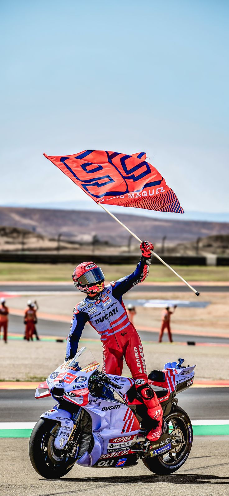 a man riding on the back of a motorcycle holding a red and blue flag over his head