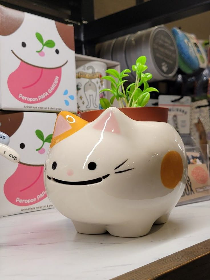 a ceramic cat planter sitting on top of a counter next to a potted plant