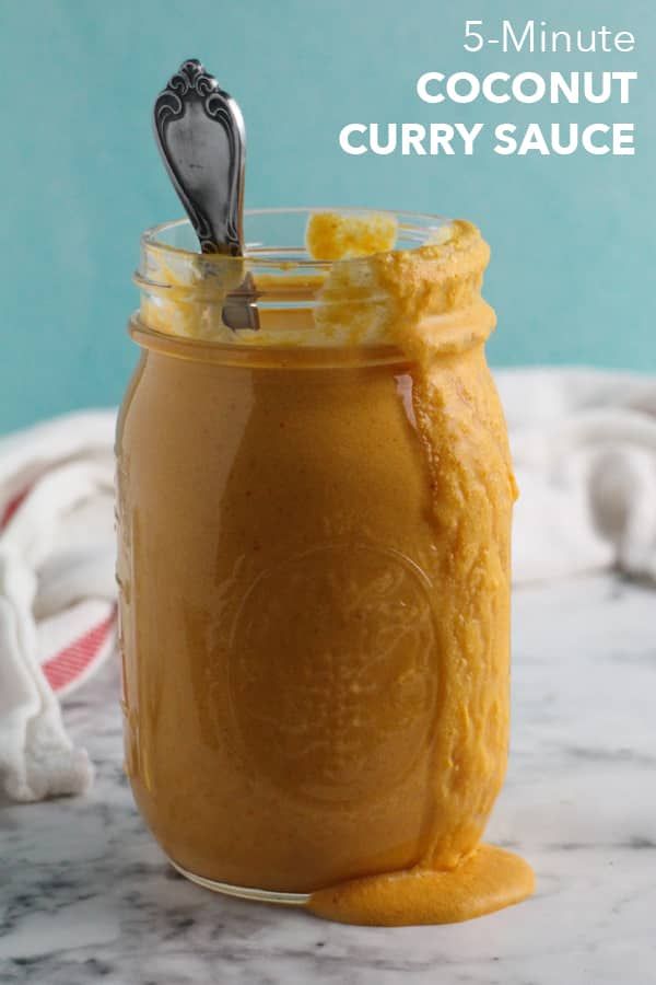 a jar filled with peanut butter sitting on top of a marble counter next to a spoon