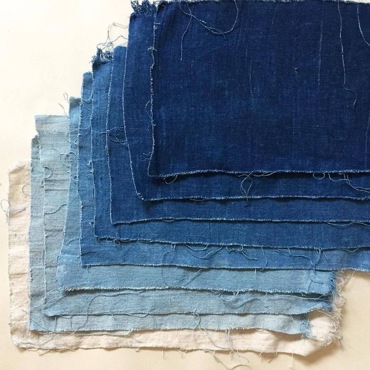 several pieces of blue fabric with frayed edges on a white surface, including one in the middle