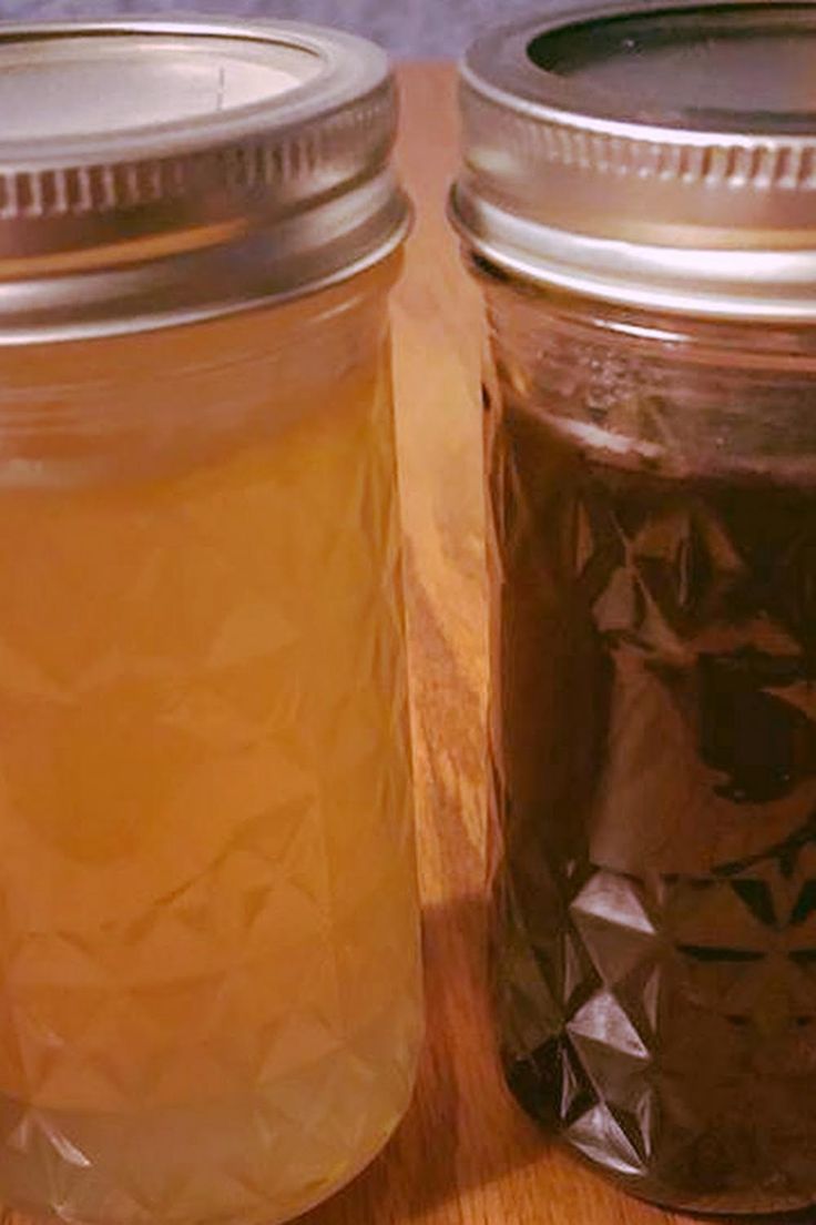 two jars filled with liquid sitting on top of a wooden table