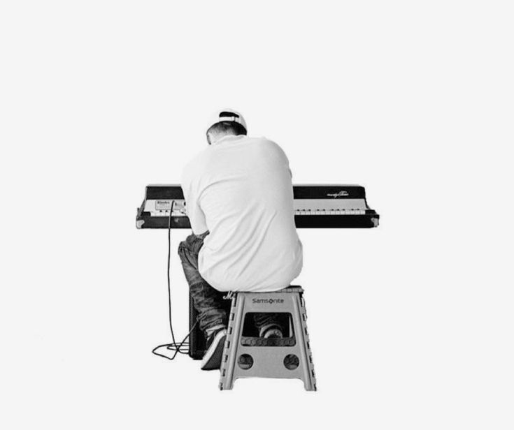 a man sitting on top of a stool next to a keyboard