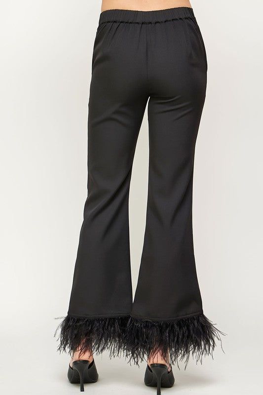 Feather trim flare trousers in stretch crepe fabric. This style features Capri flare legs, feather trim at hem, side pockets, elasticated waist at back, and zip fly with hook and bar closure. Feather Trim Flare Pants 94% Polyester 6% Spandex Matching Blouse Available Chic Feather Trim Bottoms, Feather Trim Party Bottoms For Fall, Chic Feather Trim Bottoms For Night Out, Elegant Spring Bottoms With Feather Trim, Chic Pants With Feather Trim, Elegant Fitted Bottoms With Feather Trim, Black Party Bottoms With Feather Trim, Elegant Spring Bottoms With Feathers, Black Flared Hem Pants For Party