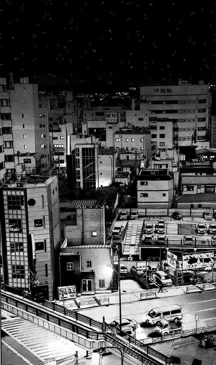 black and white photograph of city at night with cars parked on the street in front of buildings