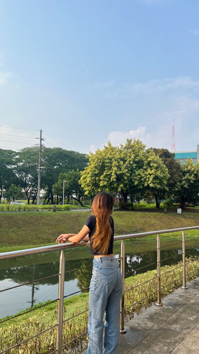 a woman is standing on a railing looking at the water