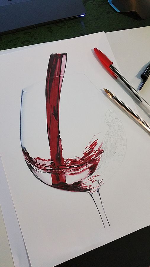 a drawing of a glass of red wine on a table with markers and pencils