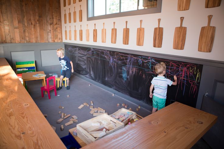 two children are playing with wooden blocks in front of a chalkboard that has writing on it