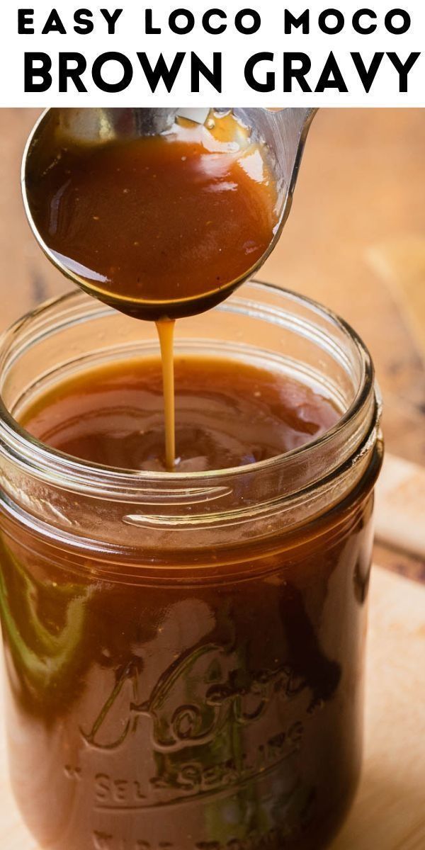 a jar filled with brown gravy sitting on top of a wooden cutting board