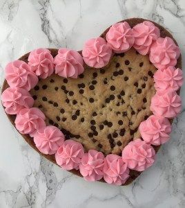 a heart shaped cookie with pink frosting on top