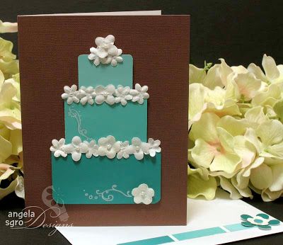 a blue and brown card with white flowers on the front, sitting next to a bouquet of hydrangeas