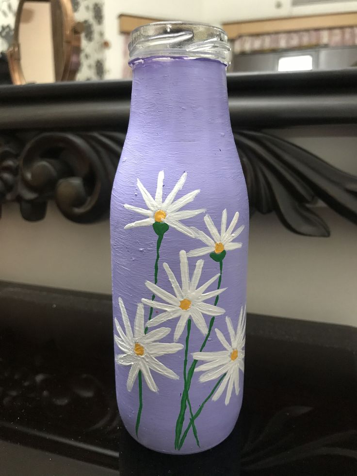 a purple vase with white daisies painted on it