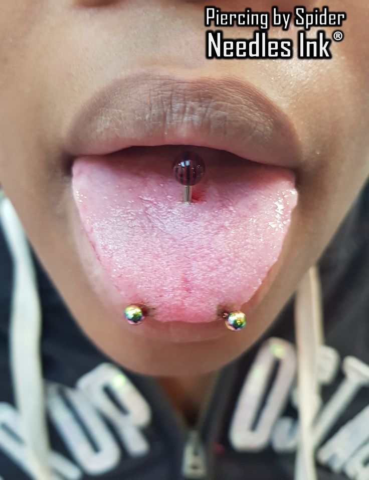 a person with piercings on their tongue sticking out from under the lip and nose