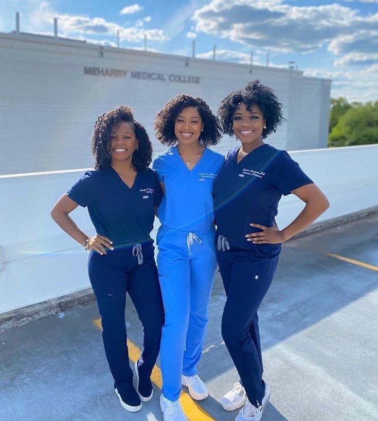 three women in scrubs are posing for a photo on the side of a building