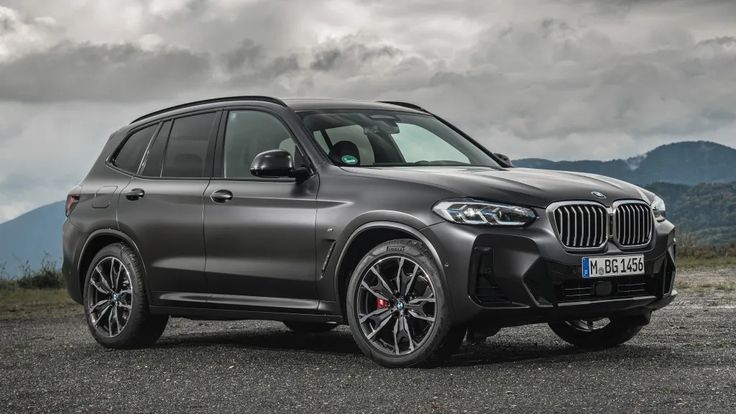 the new bmw x5 suv is parked on a gravel road