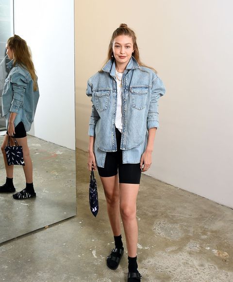 a woman standing in front of a mirror wearing black shorts and a denim jacket with pockets