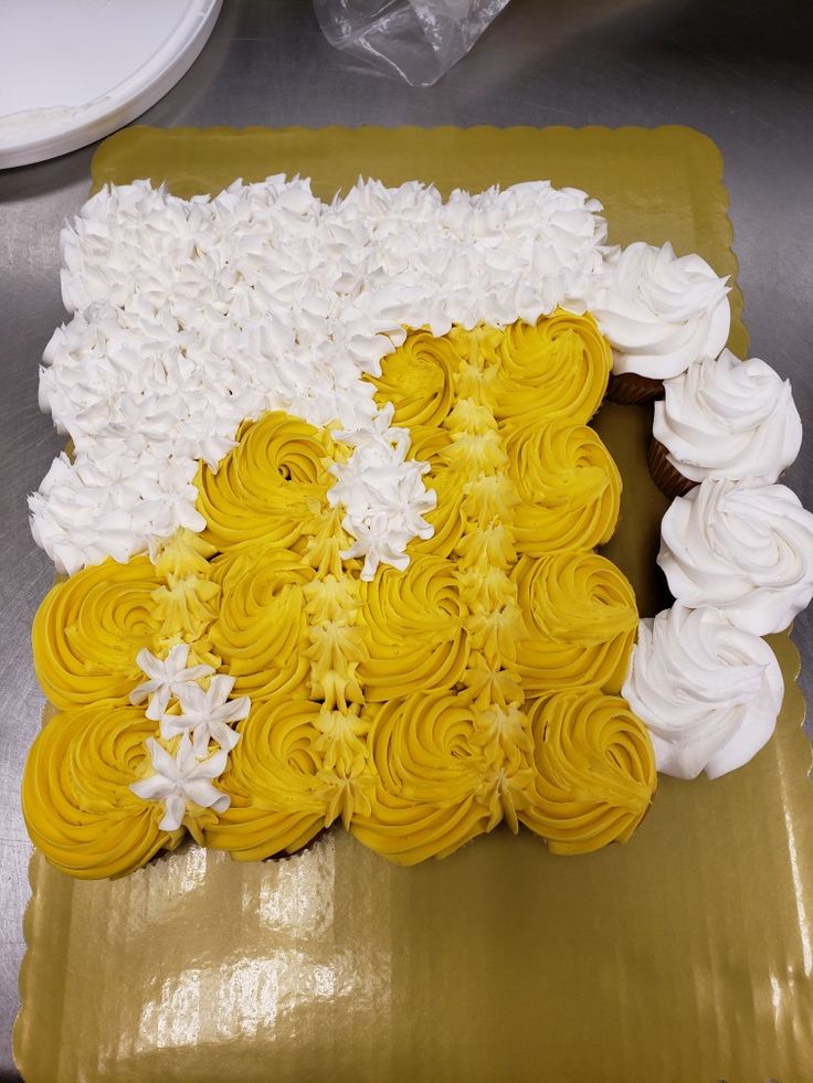 a yellow and white cake sitting on top of a plastic tray covered in frosting