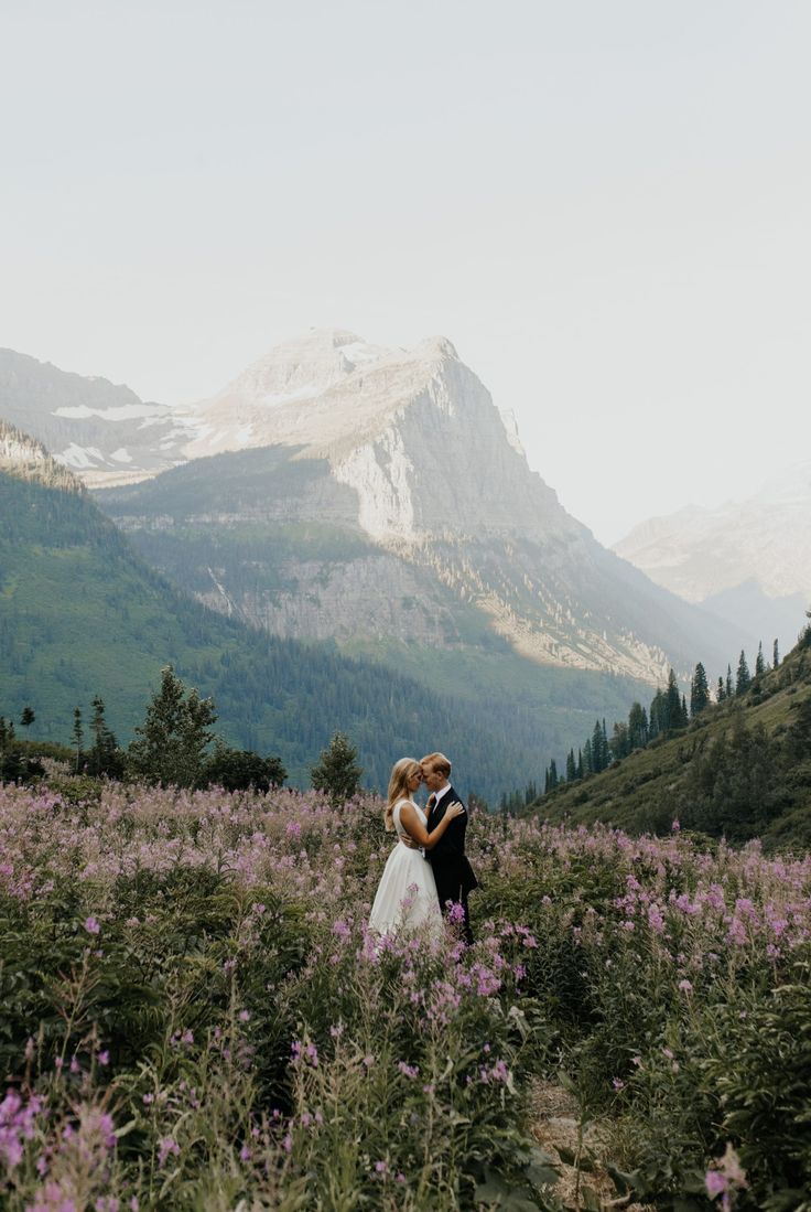 a bride and groom standing in the mountains