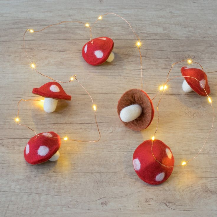 some red mushrooms with white dots on them and string lights around the mushroom's base