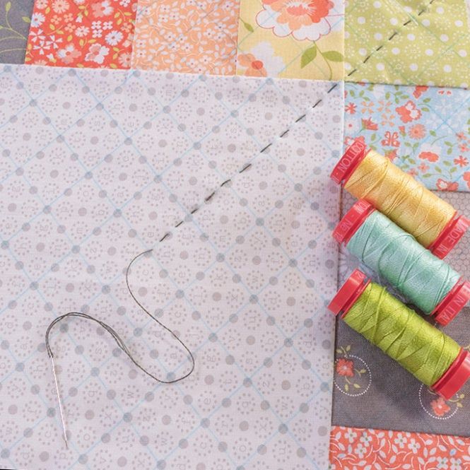 four spools of thread sitting on top of a piece of fabric