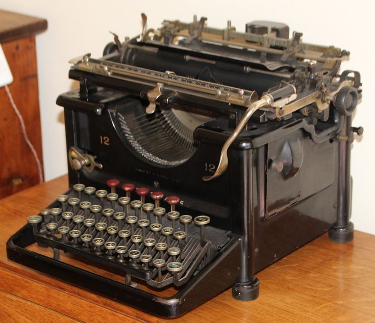 an old fashioned typewriter sitting on top of a wooden table