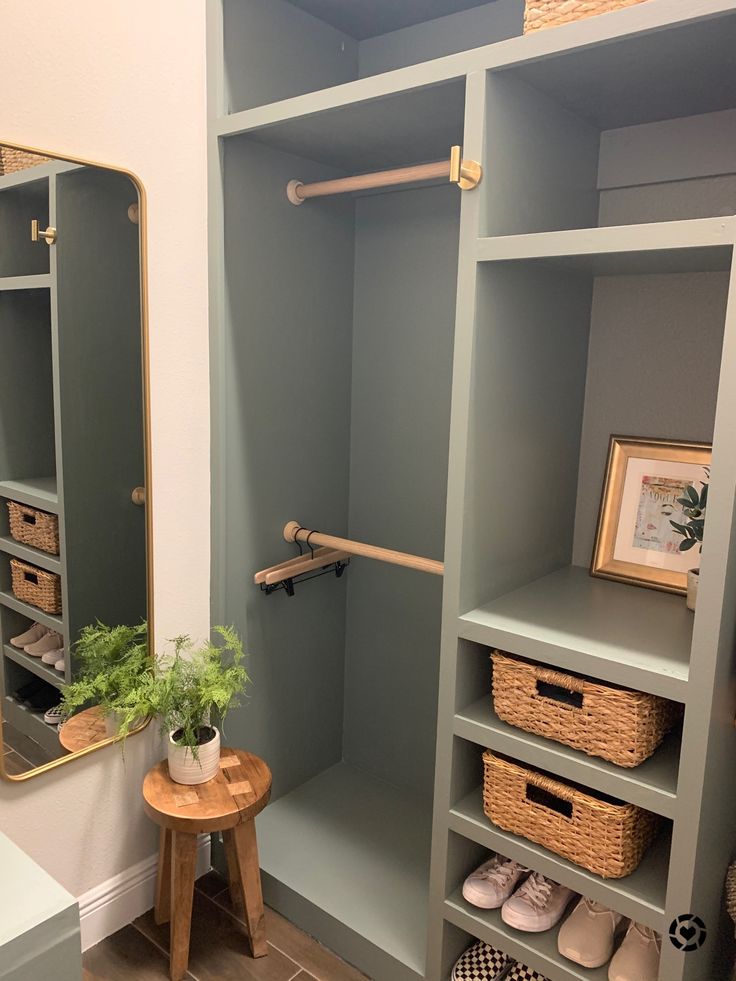 a walk in closet with shelves and baskets on the floor next to a mirror, potted plant and other items