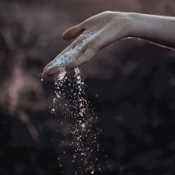 a person's hand reaching for sand on the ground