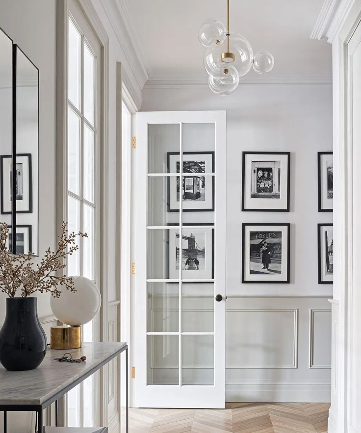 a hallway with pictures on the wall and a vase full of flowers in front of it