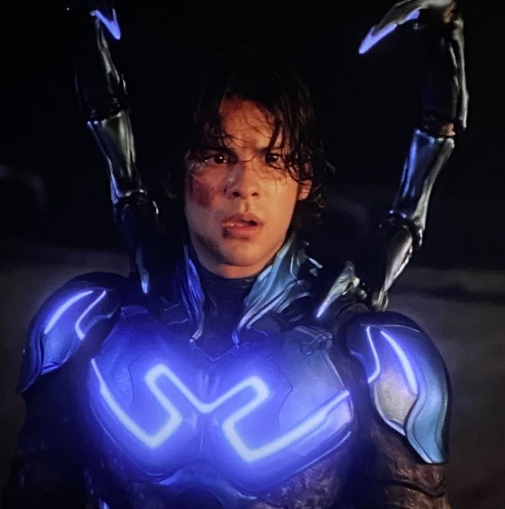 a man in futuristic suit with blue lights on his chest and arms, holding two hands up