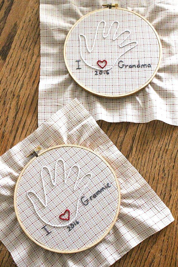 two cross stitch hand prints on napkins sitting on top of a wooden table