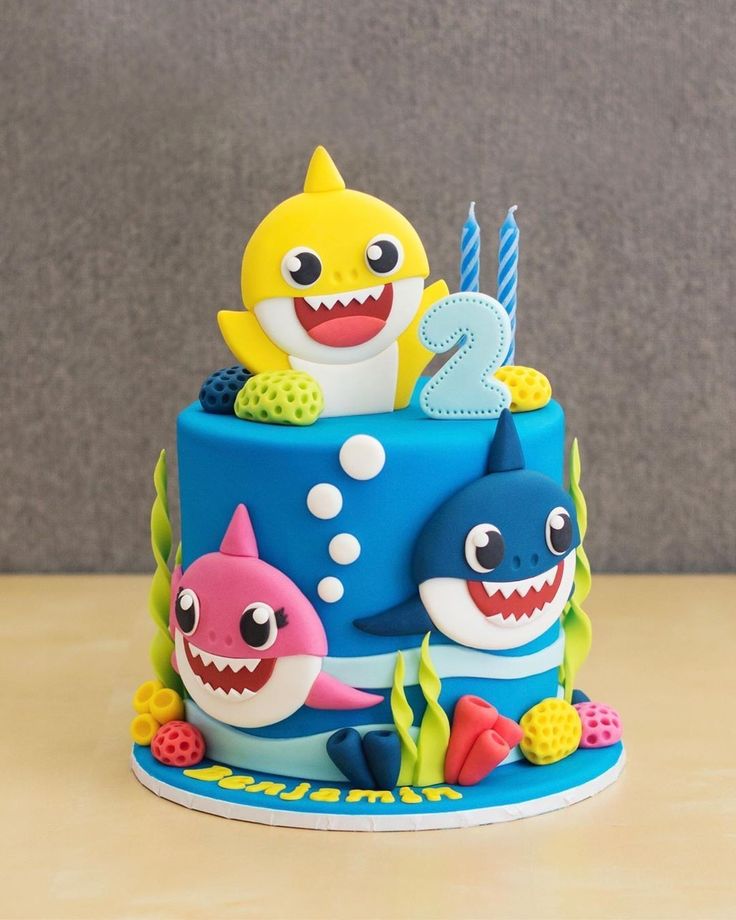 a birthday cake decorated to look like a shark and two sharks with candles on top