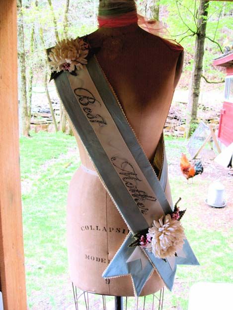 a mannequin with ribbons and flowers on it's back, sitting in front of a window