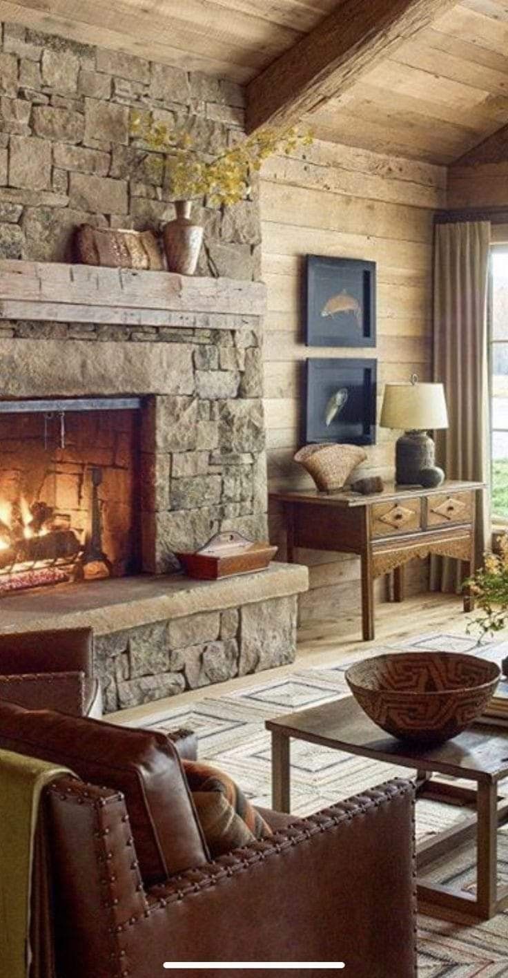 a living room filled with furniture and a fire place in the middle of a stone fireplace