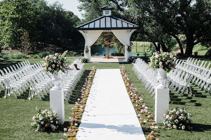 an outdoor ceremony setup with white chairs and flowers