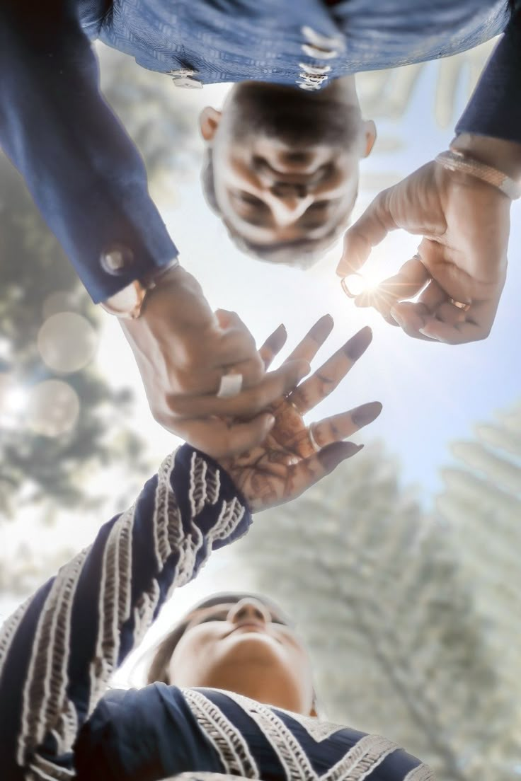 three people reaching their hands up to each other in the air with sunlight shining through them